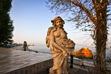 Statue of a naked girl with flowers near blue seaの写真素材