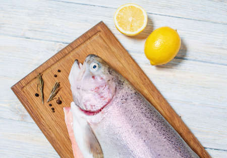 Fresh trout on a cutting board with lemon and spicesの写真素材