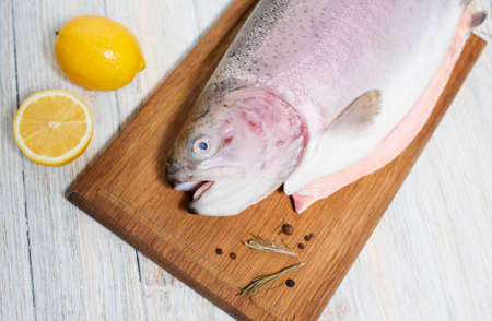 Fresh trout on a cutting board with lemon and spicesの写真素材