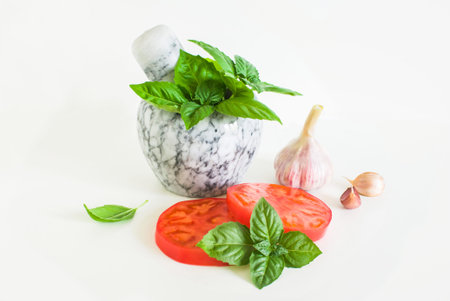 Fresh basil in a stone mortar for chopping and vegetables for salad