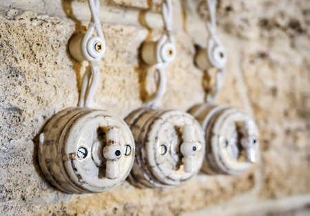 Retro electrical wiring with wires and switches on an old stone wallの写真素材