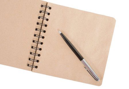 Open blank square notebook of brown kraft paper with a spiral and ballpoint pen lie on a white...