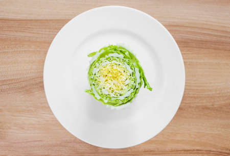 Sliced Beijing cabbage on a white plate on the table, top viewの写真素材