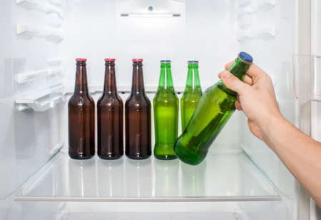 A man's hand takes out  bottles of beer from the refrigerator. close-upの写真素材