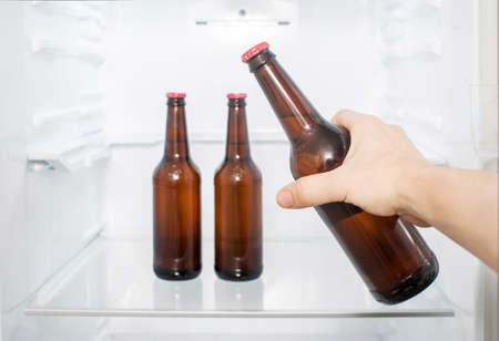 A man's hand takes a bottle of beer from the refrigerator. close-upの写真素材