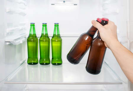 A man's hand takes out two bottles of beer from the refrigerator. close-upの写真素材