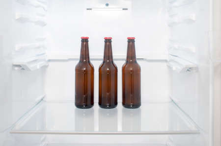 Brown glass beer bottles stand on a shelf in the refrigeratorの写真素材