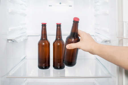 A man's hand takes a bottle of beer from the refrigerator. close-upの写真素材
