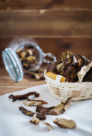Sliced dried mushrooms lie in a small wicker basket on a wooden table close-upの写真素材