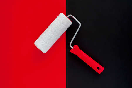 The concept of construction painting work. New clean paint roller on black and red backgroundの写真素材