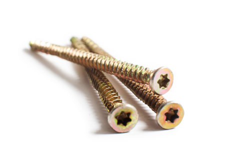 Three golden screws on concrete, isolated on white background. Macro
