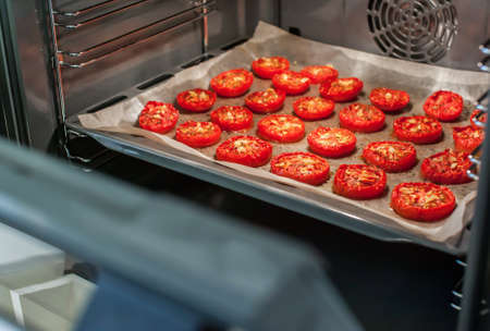 Lots of chopped sun-dried tomatoes with spices, garlic and olive oil in the ovenの写真素材