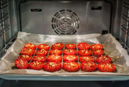 Lots of chopped sun-dried tomatoes with spices, garlic and olive oil in the ovenの写真素材