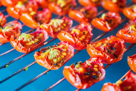Slices of sun-dried tomatoes with spices on a metal wire rack in the oven. Close-up. Macroの写真素材