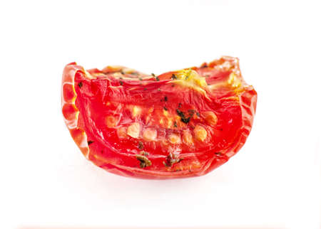 A slice of red dried tomato with spices close-up. Isolated on white background. Macro.の写真素材