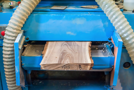 Planing boards in a carpentry workshop. Large woodworking planer