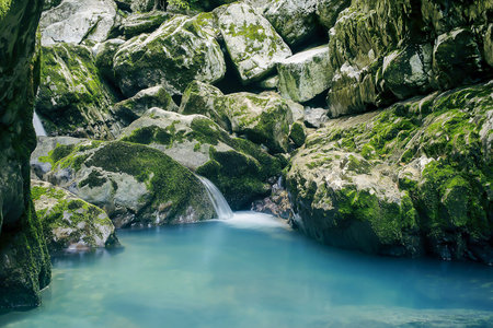 Small mountain stream, waterfall and small lake against the background of stones and green mossの写真素材