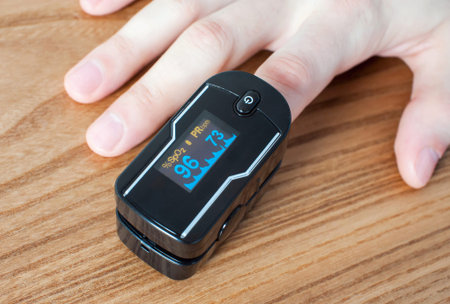 Pulse oximeter on the index finger on wooden