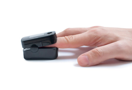 Pulse oximeter on the index finger on a white background. Measurement of blood oxygen and pulse....