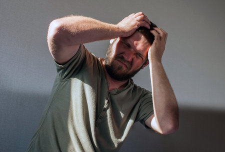 A drunk man in the morning lies on the bed with a bottle of alcohol in his hand. Hangover Syndrome....