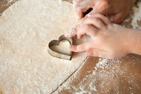 Mom and daughter prepare heart-shaped cookies together. Close-up. Form for bakingの写真素材