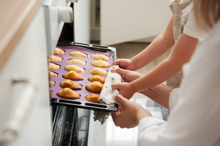The woman and her little daughter get ready-made cookies from the oven at home. Close-up