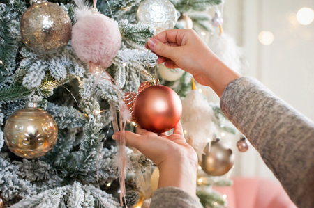 The girl hangs the ball on the Christmas tree and decorates it for Christmas and New Year. Close-up