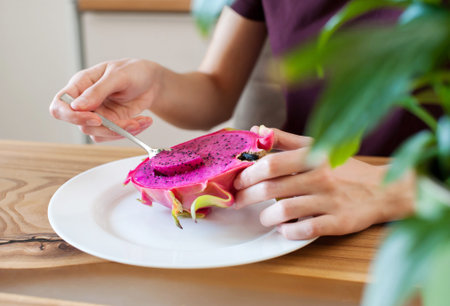 The girl holds in her hands a cut dragon fruit pitahaya at home in the kitchen close-up. soft focus