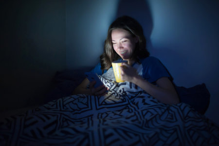 The girl lies at home in the evening on the bed with a phone in the dark. defocus