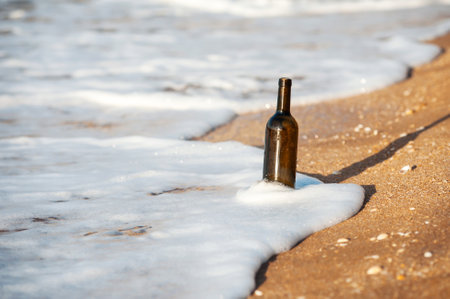 a bottle of wine on a sandy beach against the background of the surfの写真素材