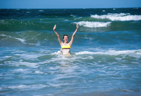 A woman in a swimsuit rejoices and has fun in the sea on the wavesの写真素材