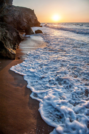 Sea surf in the evening at sunset on a wild deserted rocky beachの写真素材