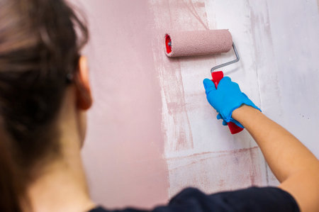 Young woman painting a wall with a paint rollerの写真素材