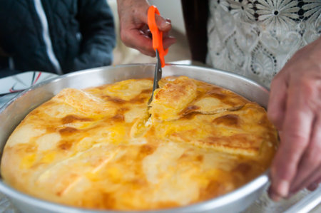 Woman cutting fresh delicious cheese pie khachapuri close upの写真素材