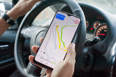 Smartphone with navigation on the screen in the hand of a car driver close-upの写真素材