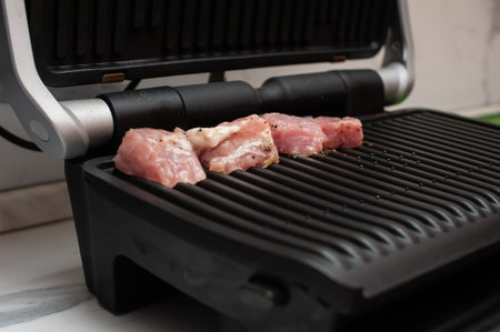 pork is fried on a modern electric grill in the kitchen close-upの写真素材