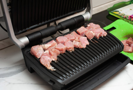 pork is fried on a modern electric grill in the kitchenの写真素材
