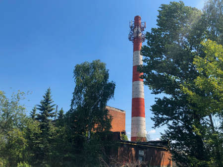 Industrial chimney. To minimize the harmful impact on the surrounding area, the chimney is made very tall. The smoke mixed with the air and the concentration of harmful substances becomes lower.の写真素材