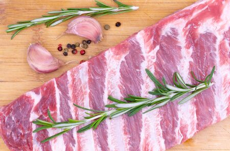Raw fresh pork ribs with rosemary and spices on a wooden board. Fresh meat.の写真素材