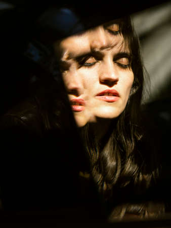Reflection of the face of a mysterious girl in a shard of a mirrorの写真素材