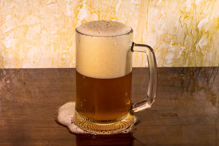A glass of beer that has partially spilled onto the tableの写真素材
