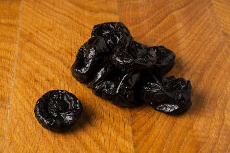 a bunch of prunes, dried fruit lies on a wooden boardの写真素材