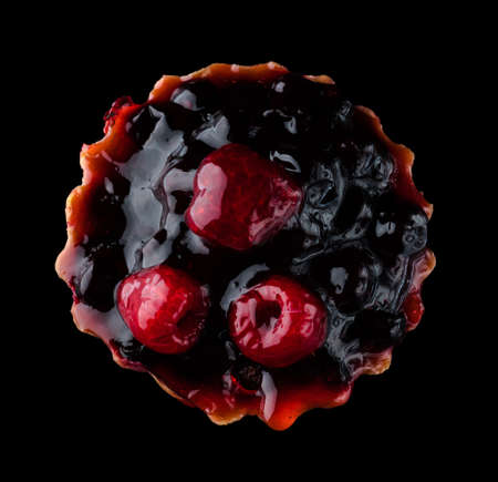 Pastry stuffed with fruits, berries and citrus fruits on a black background in isolation, view from the top, confectionery product.の写真素材