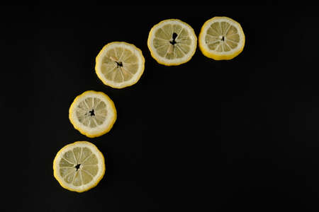 Five lemon slices lined up in a semicircle on a black background isolatedの写真素材