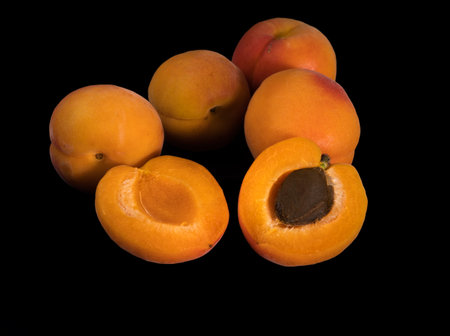A bunch of ripe Apricot fruits, whole and slices, on a black backgroundの写真素材