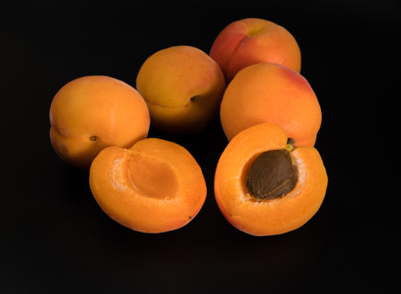 A bunch of ripe Apricot fruits, whole and slices, on a black backgroundの写真素材