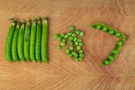 Whole stitches of peas and also separately grains, of peas scattered on a wood board