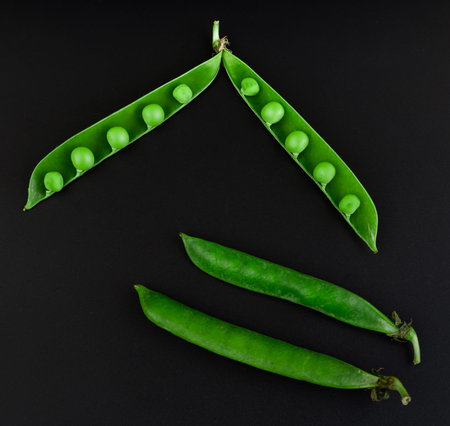 Two whole peas and one open stitch of peas with grains, on a black background