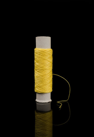 A skein of thread, a spool of thread for sewing, on a black background with reflection