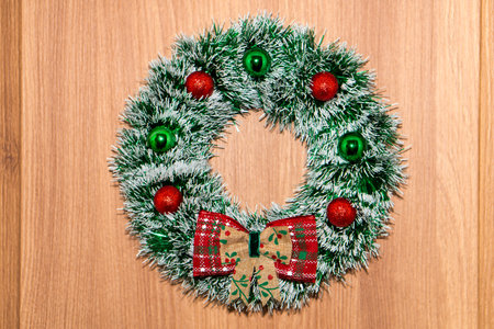 Christmas wreath hanging on a wooden door, decorated with bows.の写真素材